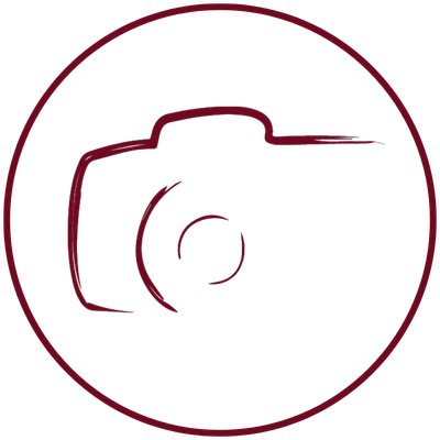 Eine schlichte, kastanienbraune Umrisszeichnung einer Kamera in einem Kreis auf hellgrauem Hintergrund – ideal zur Darstellung einer Hochzeitsfotografin aus Gießen oder für alle, die einen Hochzeitsfotografen aus Gießen suchen.